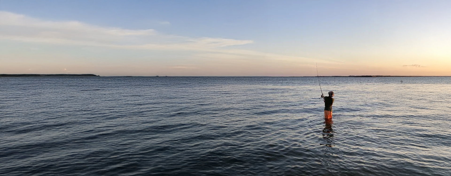 Standing in the water, a person uses gear from Charleston Fishing Rentals for surf fishing gear rental Charleston.