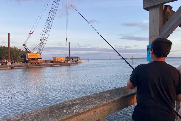Near the dock, a man fishes using fishing rod and reel rental Charleston from Charleston Fishing Rentals.