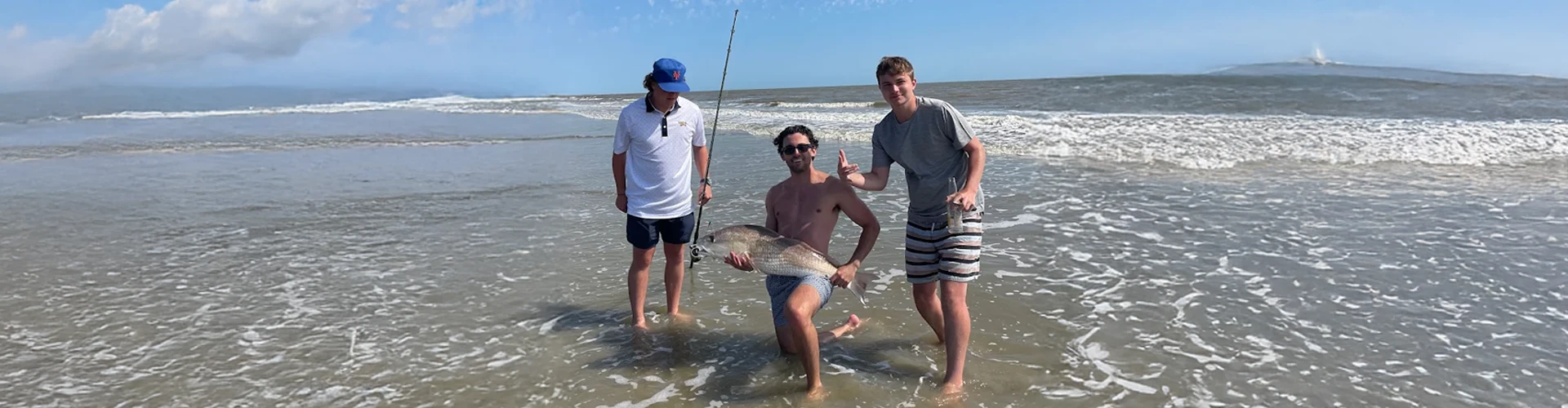 A man and children in the water use beach fishing equipment rental Charleston from Charleston Fishing Rentals.