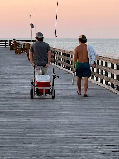 Walking along the pier, a man uses fishing rod and reel rental Charleston from Charleston Fishing Rentals.