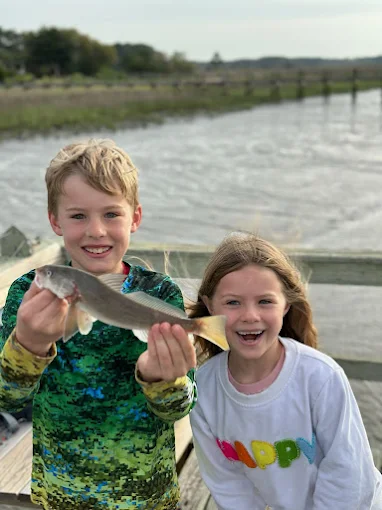 Children holding fish on a dock use fishing gear rentals Charleston SC from Charleston Fishing Rentals.