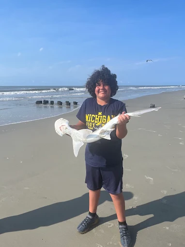 A boy holding a fish uses fishing rod and reel rental Charleston from Charleston Fishing Rentals.